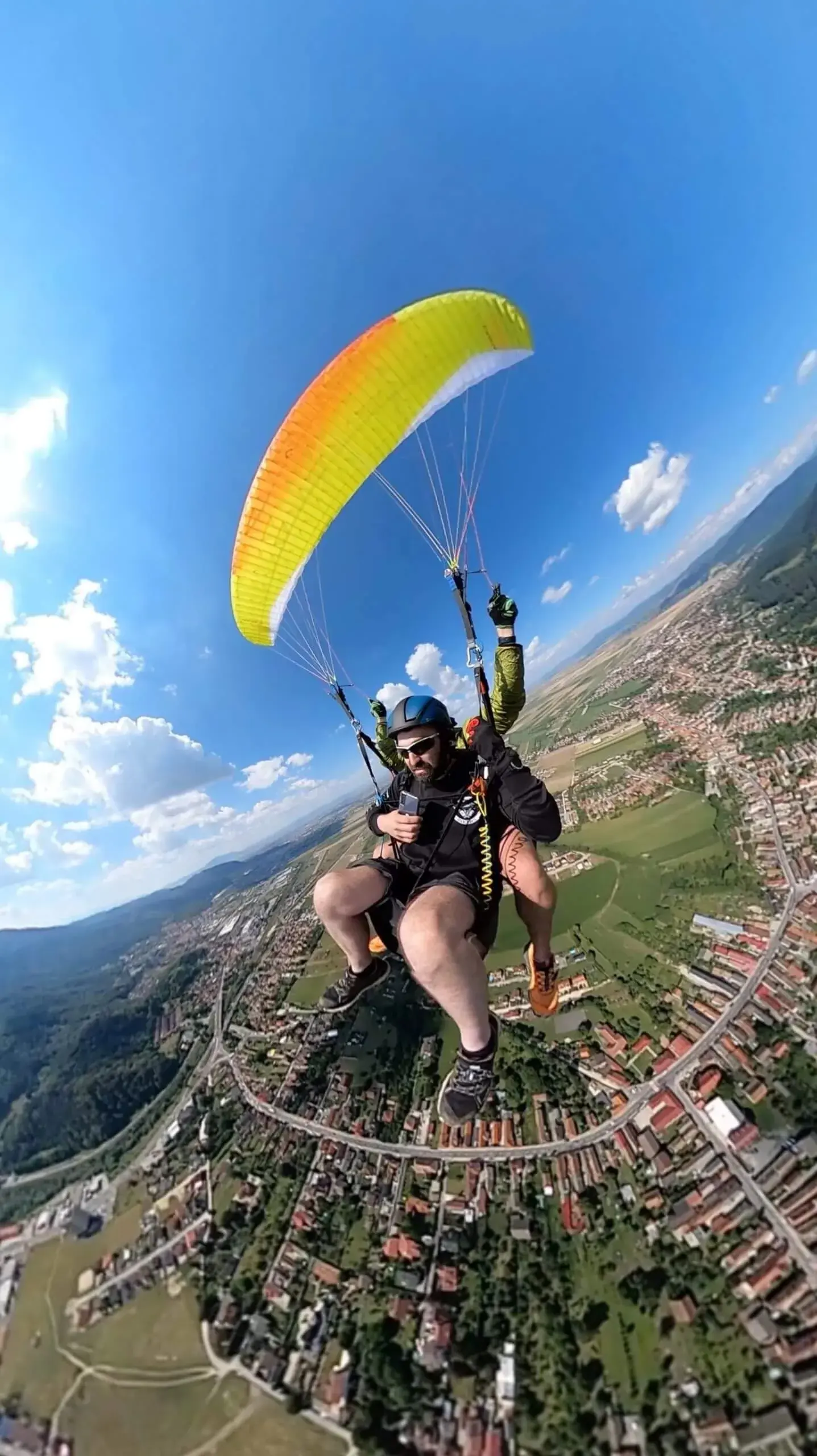 Aripă portocalie de parapantă deasupra orașului, vara