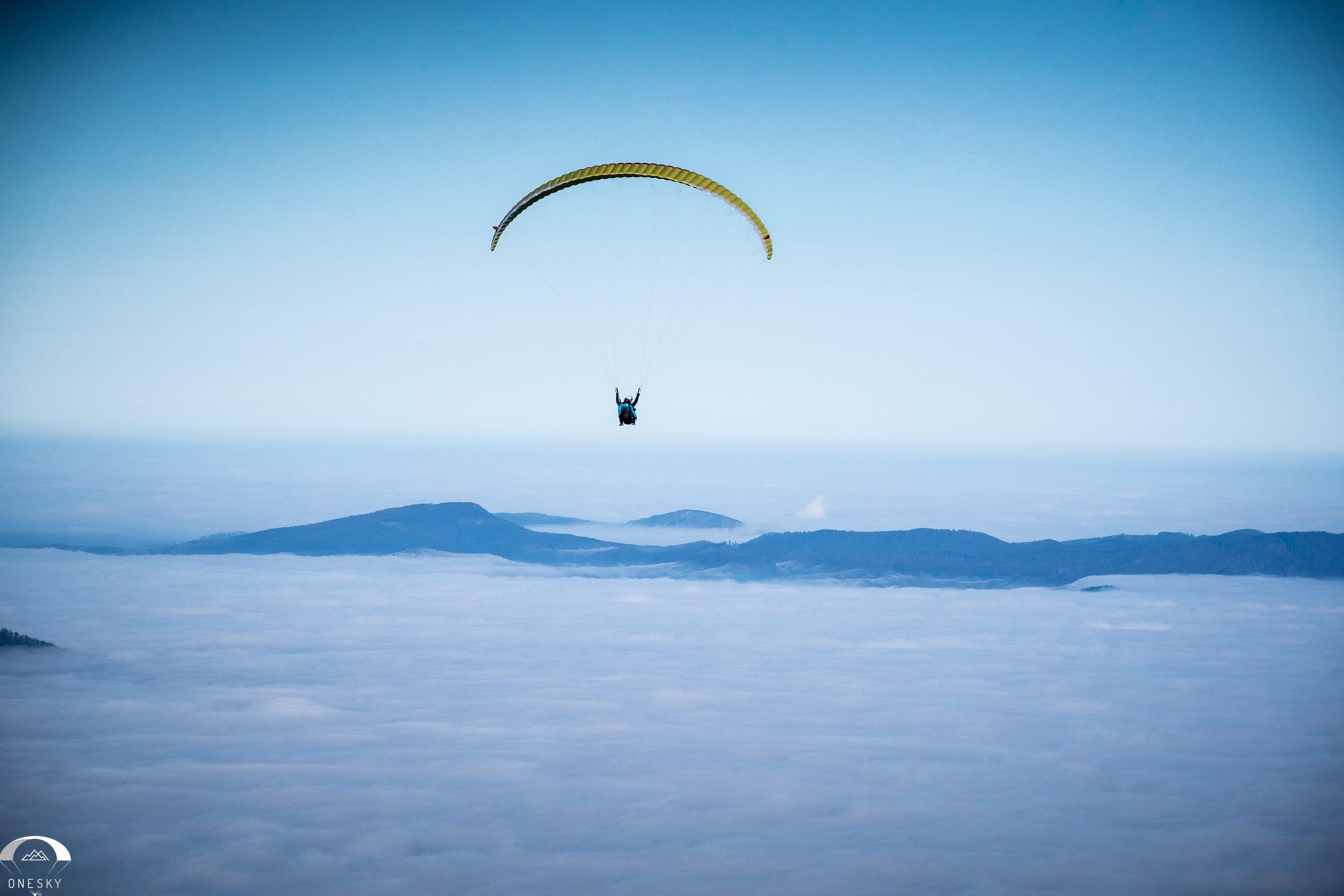 Parapantă plutind deasupra mării de nori
