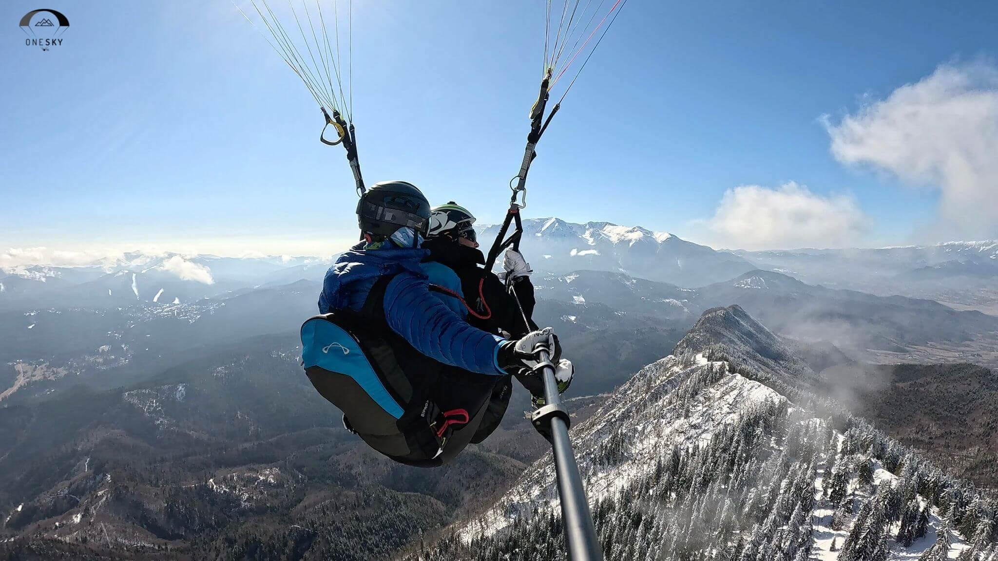 Zbor în tandem de-a lungul crestei înzăpezite, cu munții în fundal