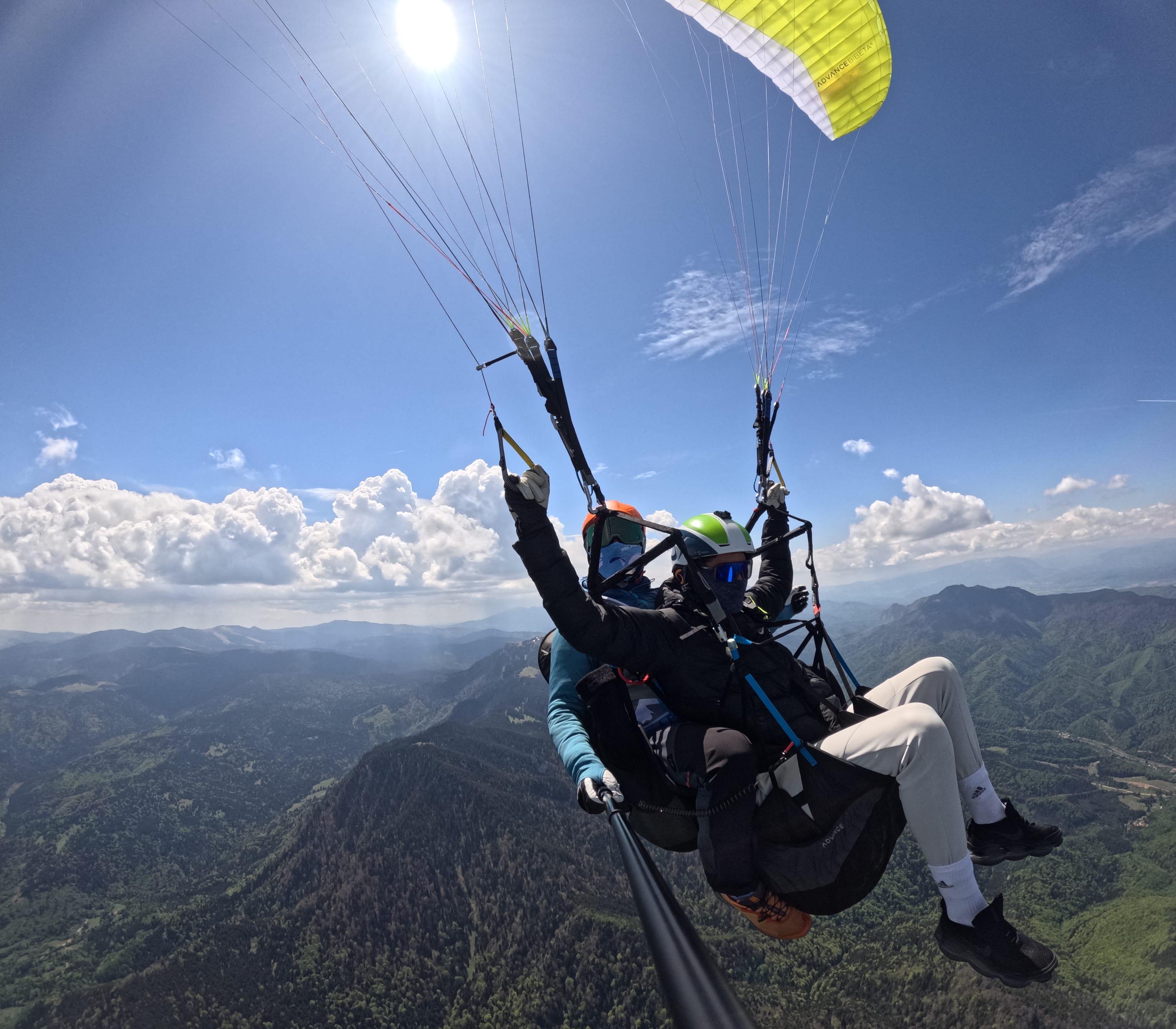 Pasager cu mâinile ridicate în zbor tandem, deasupra crestelor verzi