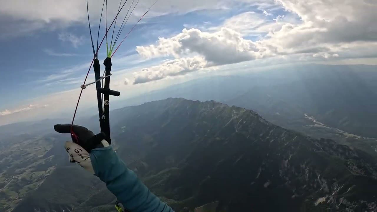 The pilot's view above a long mountain ridge, with summer clouds and the valley in the distance